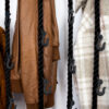 Seilgarderobe aus schwarzen Seilen und Haken hängt herunter. Auf der Garderobe hängen verschiedene Jacken.